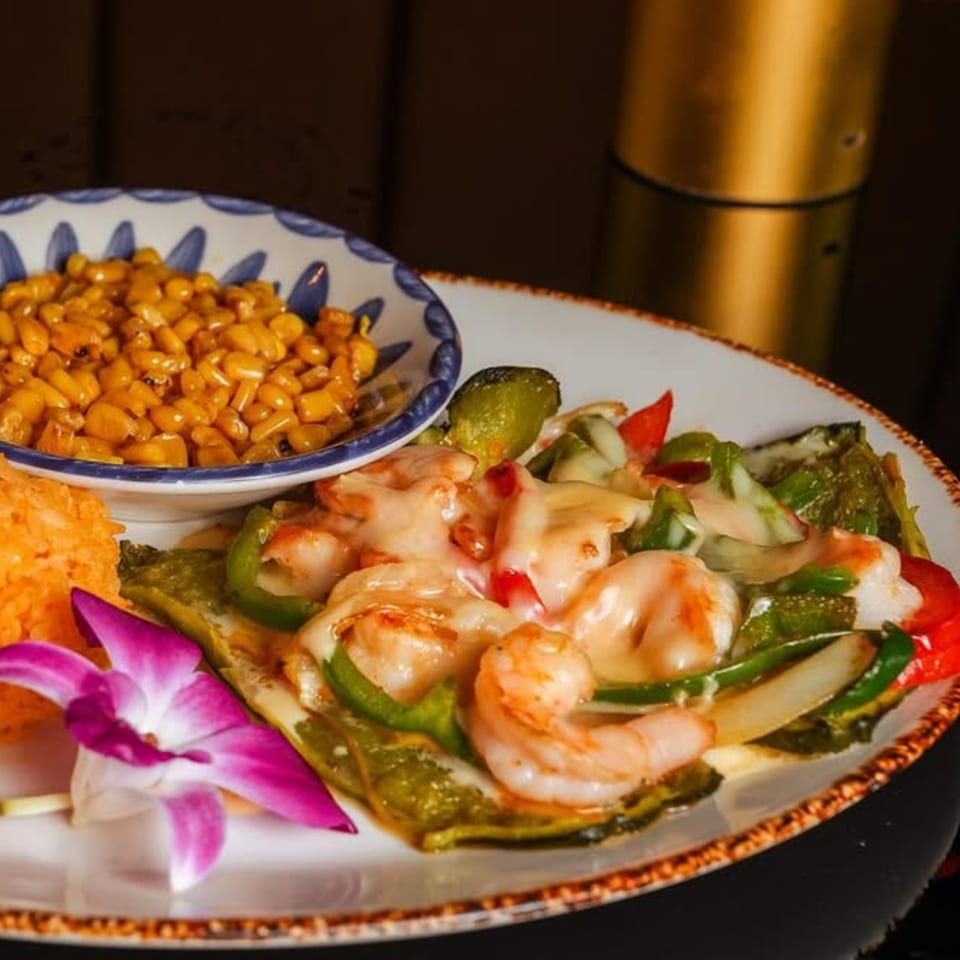 Mezcal's shrimp fajitas with melted cheese, bell peppers, onions, rice, and a side of corn.