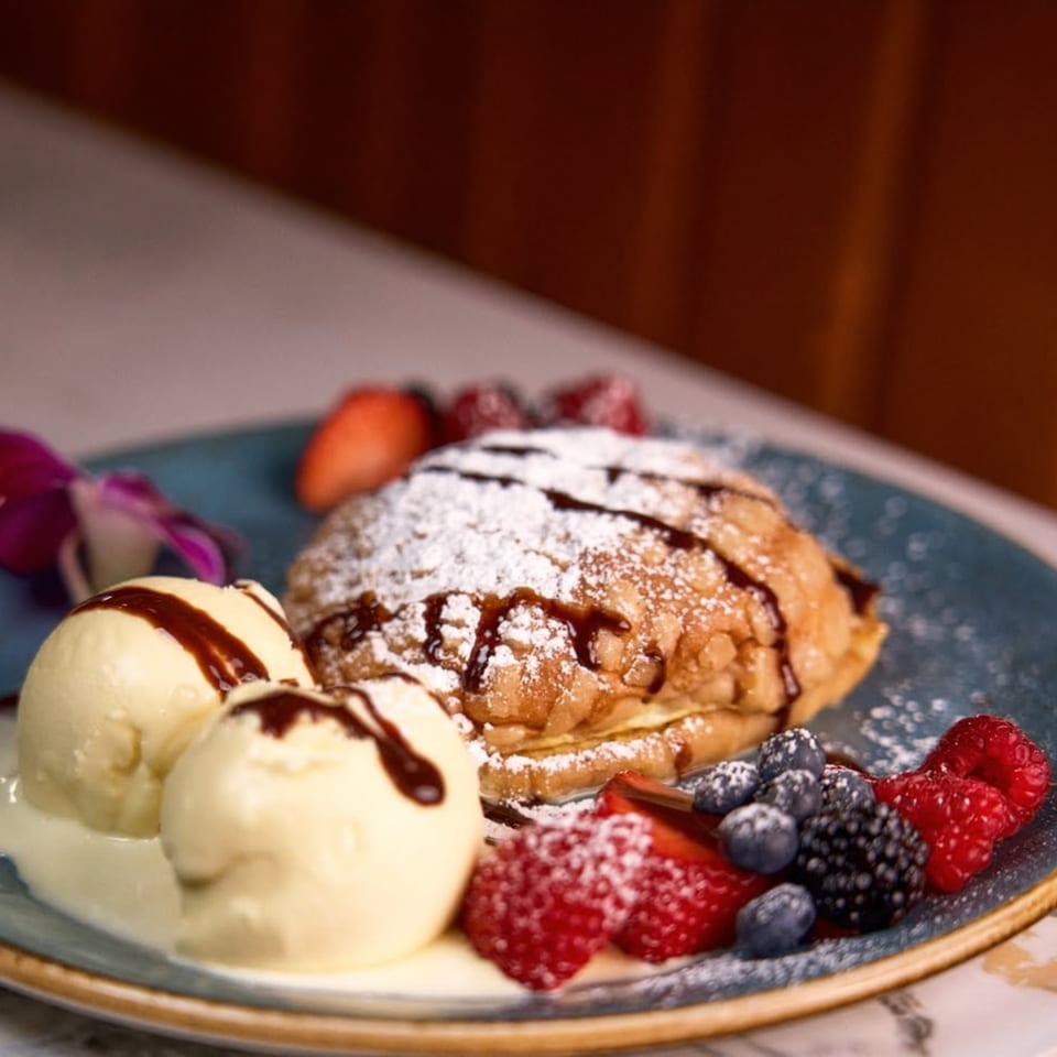Mezcal's Mexican dessert with fried pastry, vanilla ice cream, berries, and chocolate drizzle.